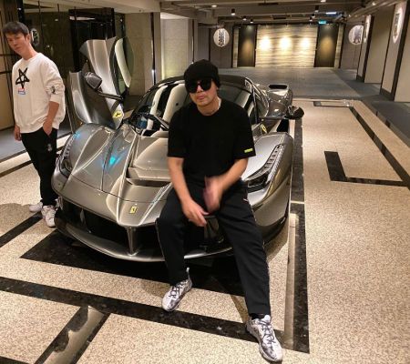 Jay Chou in a black t-shirt poses in front of his LaFerrari.